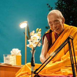 Venerable Geshe Kelsang smiling with blue background image