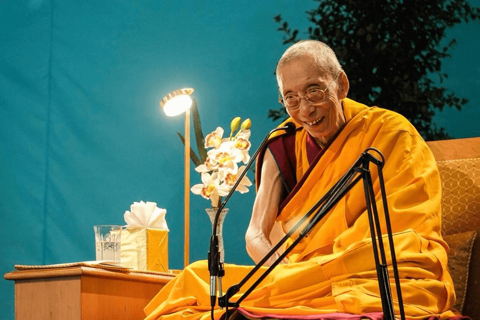 Venerable Geshe Kelsang smiling with blue background image